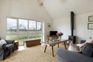 A living room with a large window, a television, a fireplace, and a sofa.