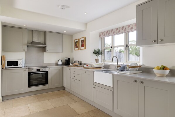A modern kitchen with built-in appliances, a sink, and a window with a view. - Cotswold country cottage -2 Manor Farm (Hook Norton, near Chipping Norton)
