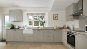 A kitchen with a large island, built-in appliances, and a window with a view. - Pet Friendly Rural Cotswold Cottage - 1 Manor Farm Cottage (Hook Norton, Banbury)