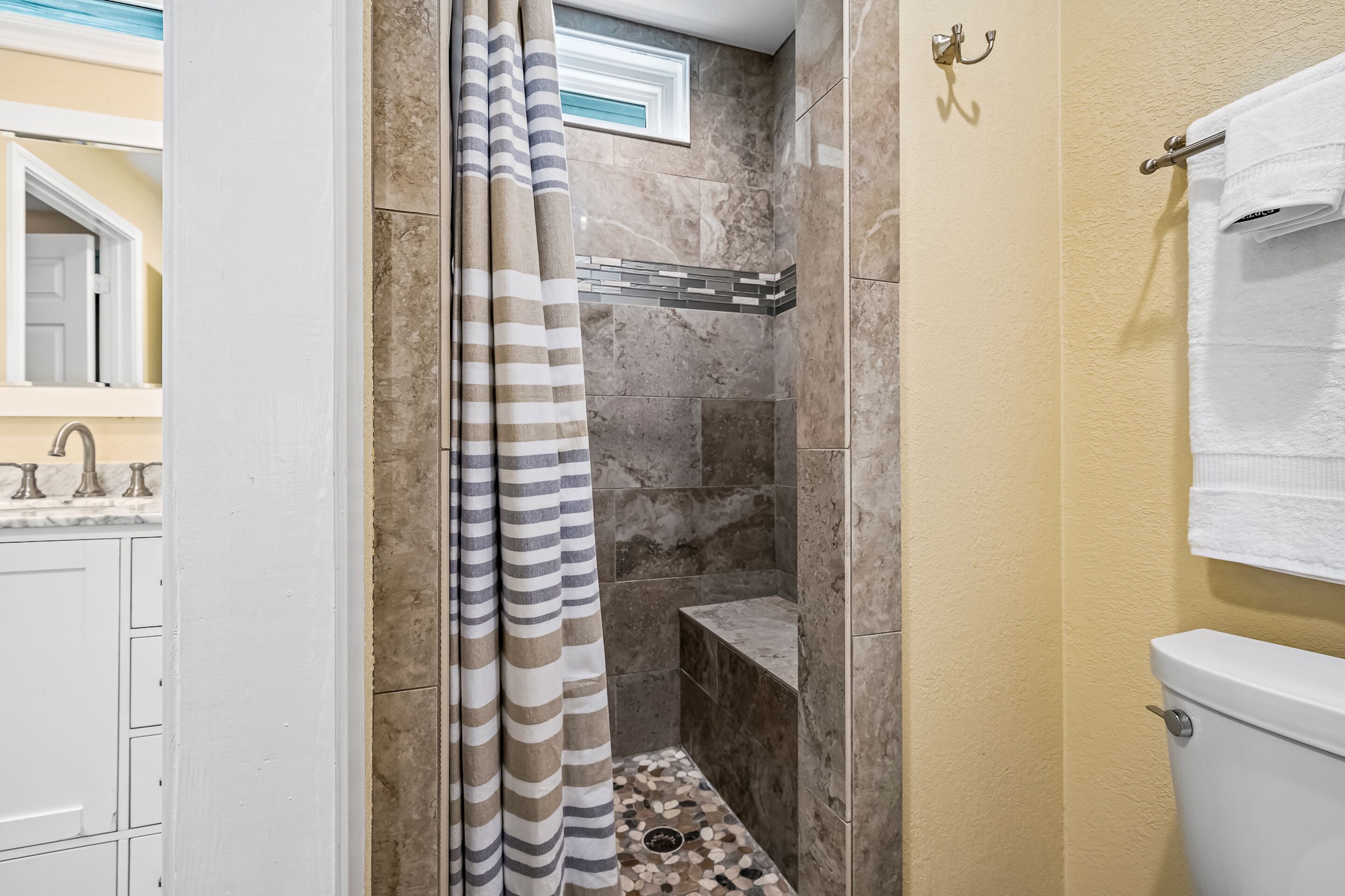Une salle de bain avec une douche, des murs carrelés, des toilettes et un porte-serviettes.