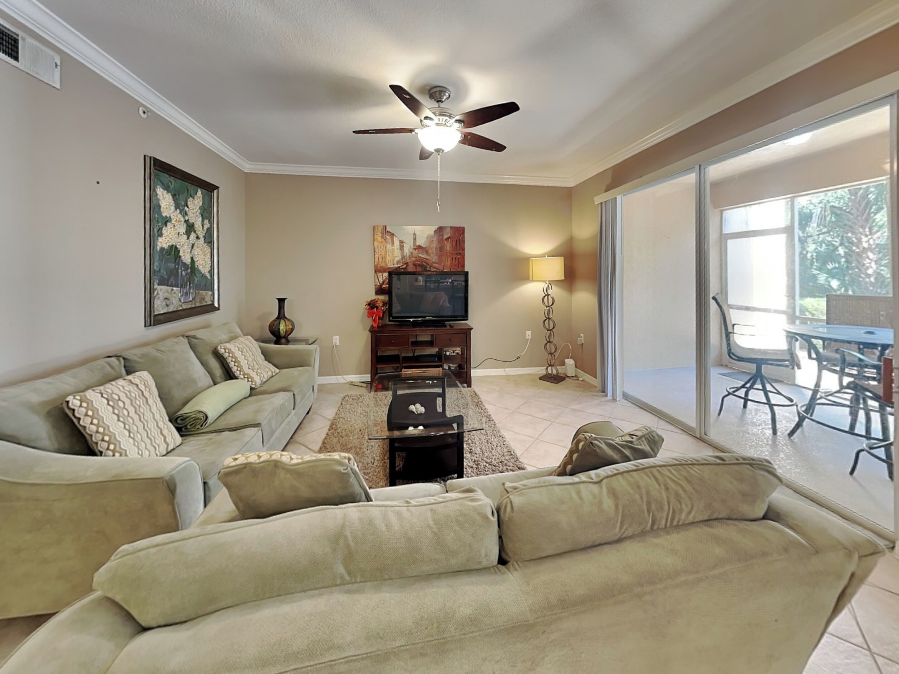 A living room with a sofa, TV, and a ceiling fan.