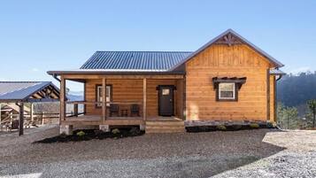 Situated in a scenic location, this cabin-style building features a covered porch with seating and a welcoming entrance.