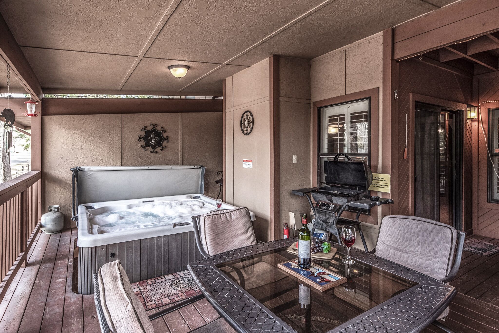 Un bain à remous, un espace salon et un barbecue sur une terrasse en bois.