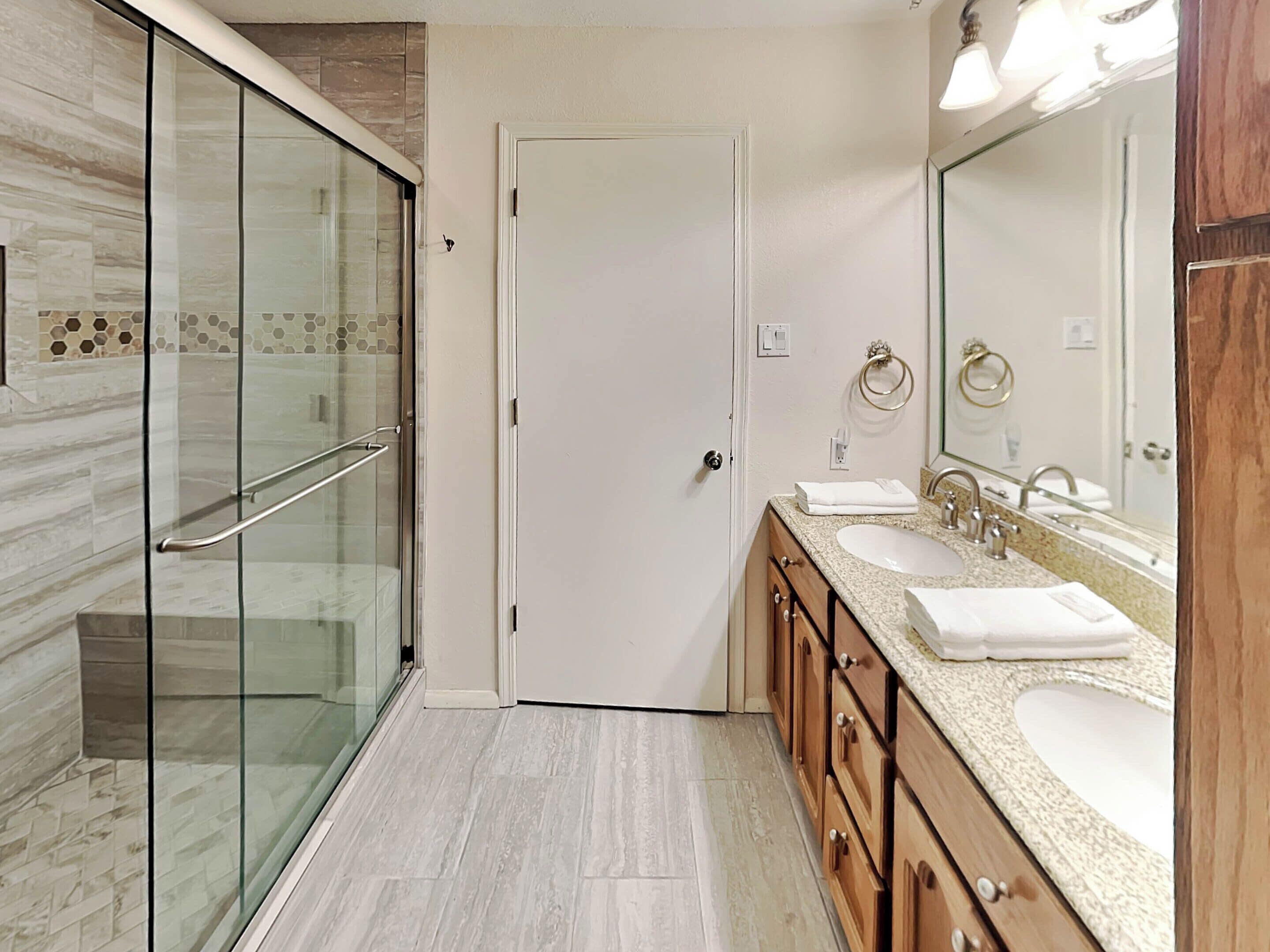 A modern bathroom with a glass shower enclosure, a double sink vanity, and a large mirror.