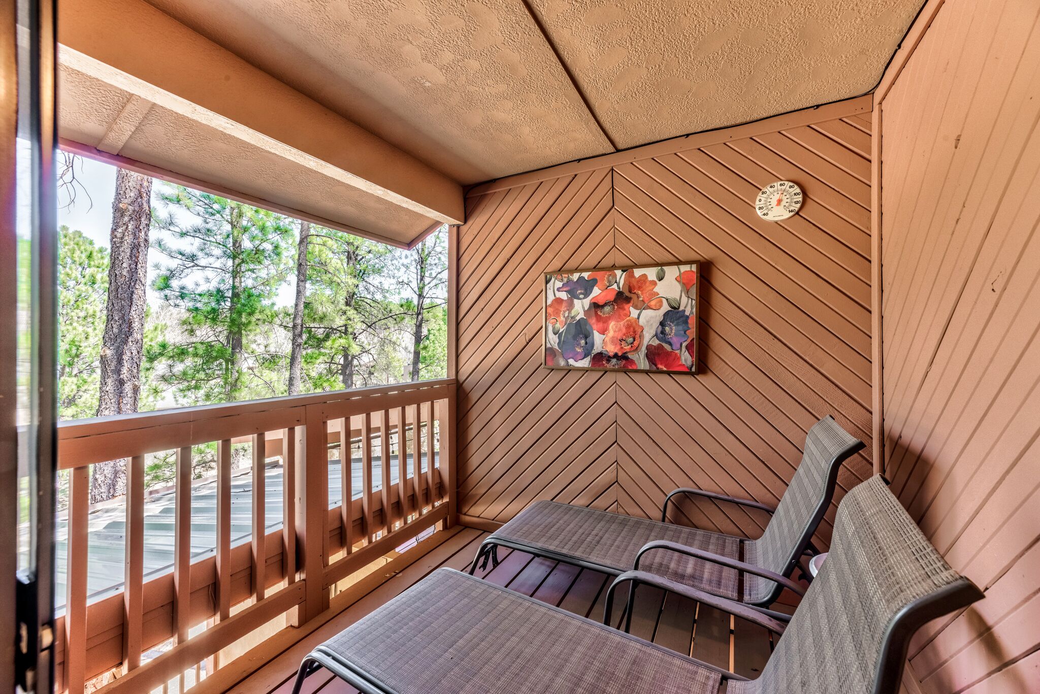 Un espace extérieur abrité, doté de sièges, de rampes en bois et d’un mur orné d’un motif en chevrons.