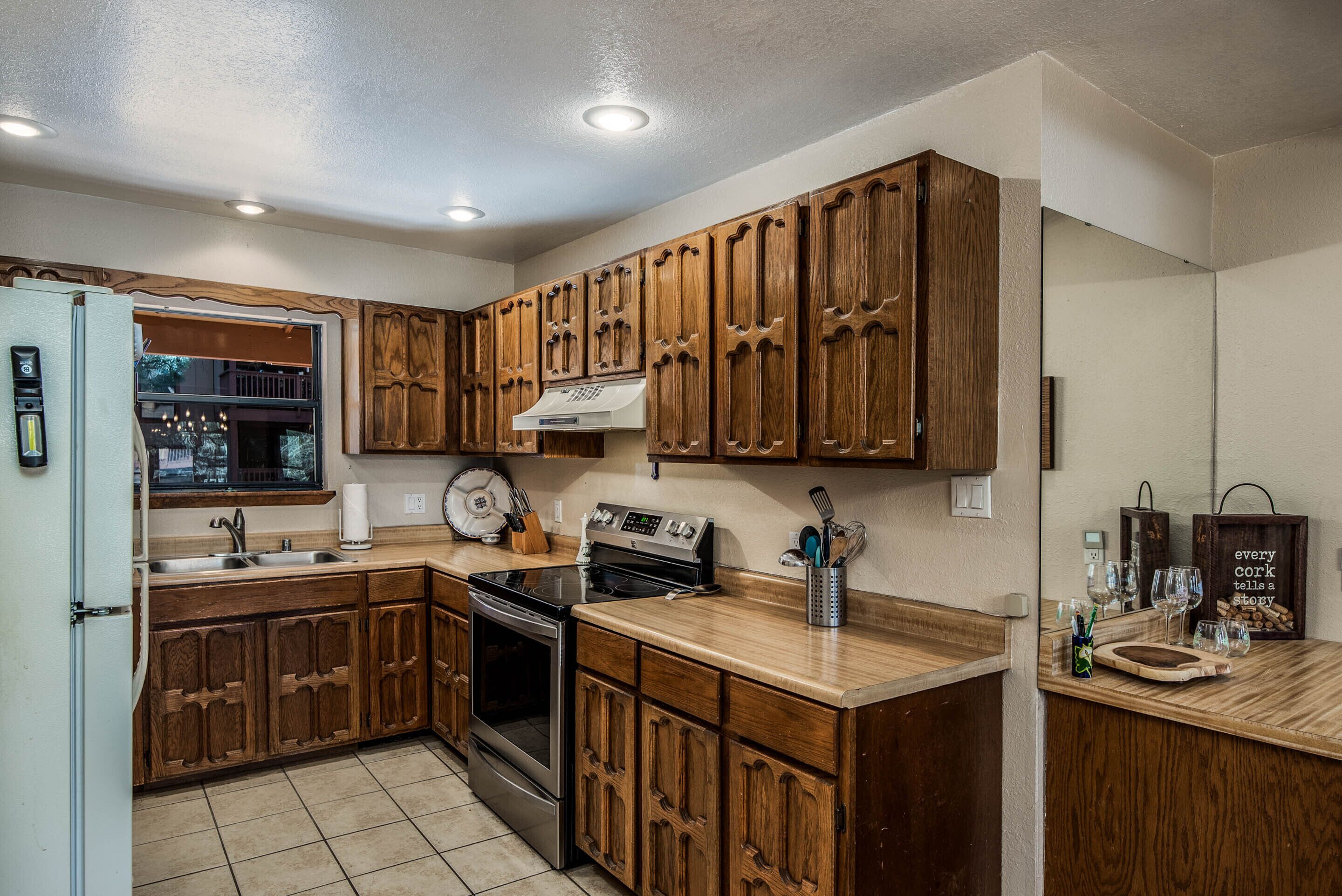 A kitchen with wooden cabinets, a stainless steel oven, and a window overlooking a balcony.