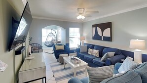 A living room with a sofa, coffee table, TV, and a ceiling fan.