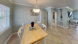 A dining area with a wooden table, white chairs, a chandelier, and a view of the outside.