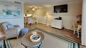 Un soggiorno con zona pranzo, una TV a schermo piatto montata a parete e una ventola a soffitto.