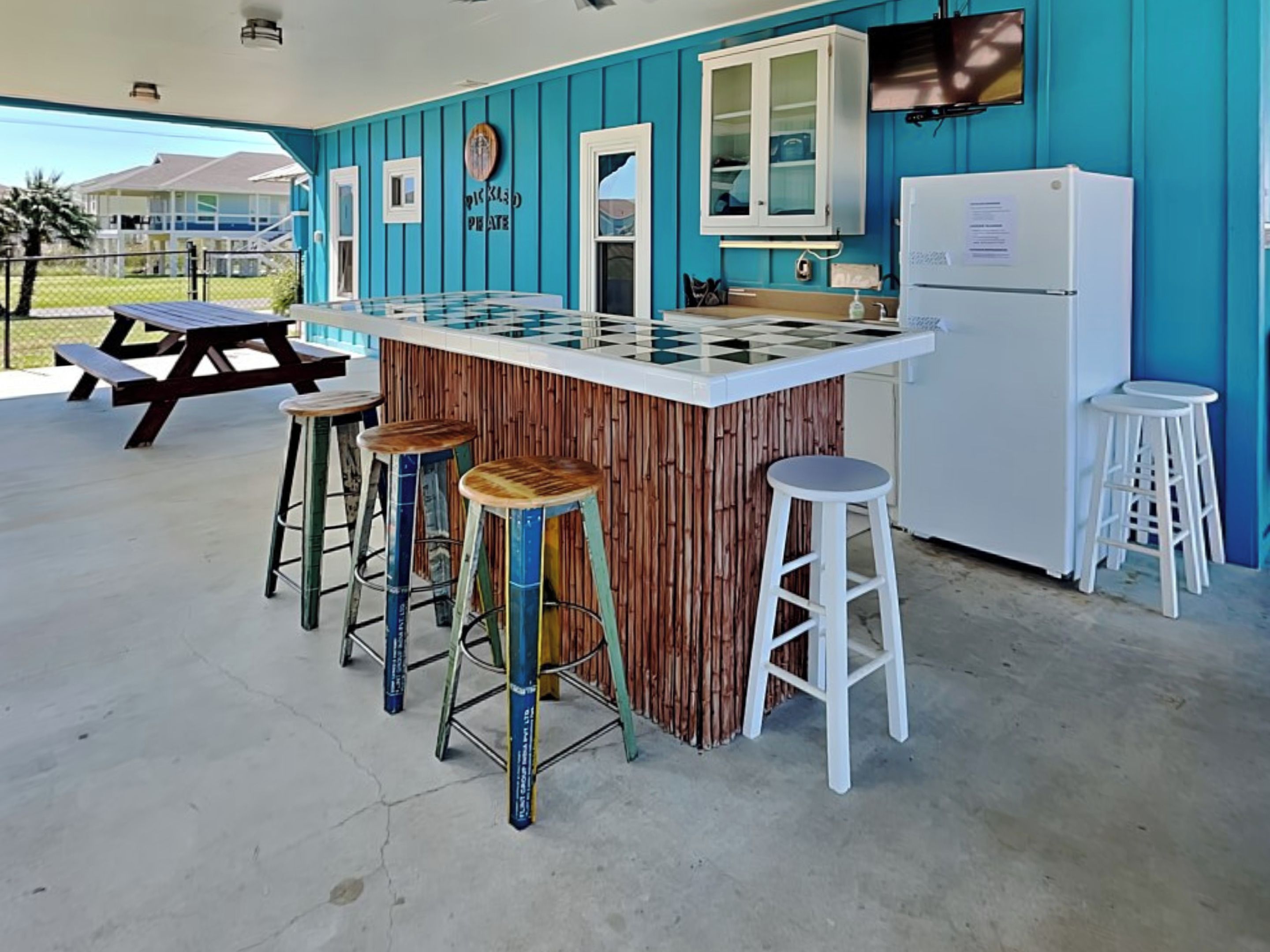 A kitchen area with a checkered countertop, a refrigerator, and bar stools.