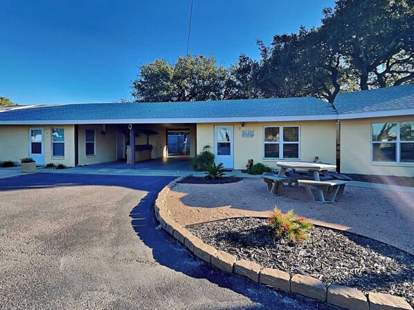 A motel with a covered parking area, a picnic table, and a landscaped garden. - Harbor Lights Cottages #3 by Miss Kitty’s (Fulton)