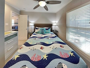A bedroom with a bed, a ceiling fan, a nightstand, a dresser, and a window with blinds. - Harbor Lights Cottages #3 by Miss Kitty’s (Fulton)