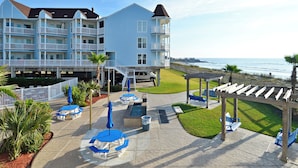 A beachfront hotel with multiple balconies, outdoor seating, and a pool area. - Abundant Relaxation by Ryson Vacation Rentals (Galveston)