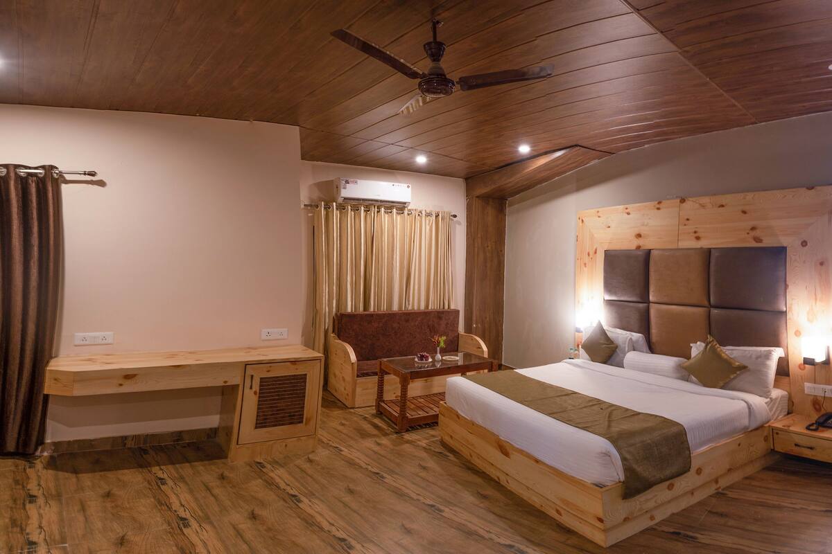 A wooden-themed bedroom with a bed, a desk, a chair, and a window.
