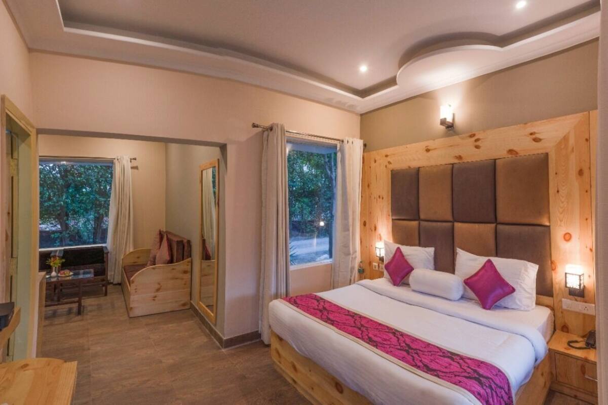 A bedroom with a bed, bedside tables, a mirror, and a window with curtains.