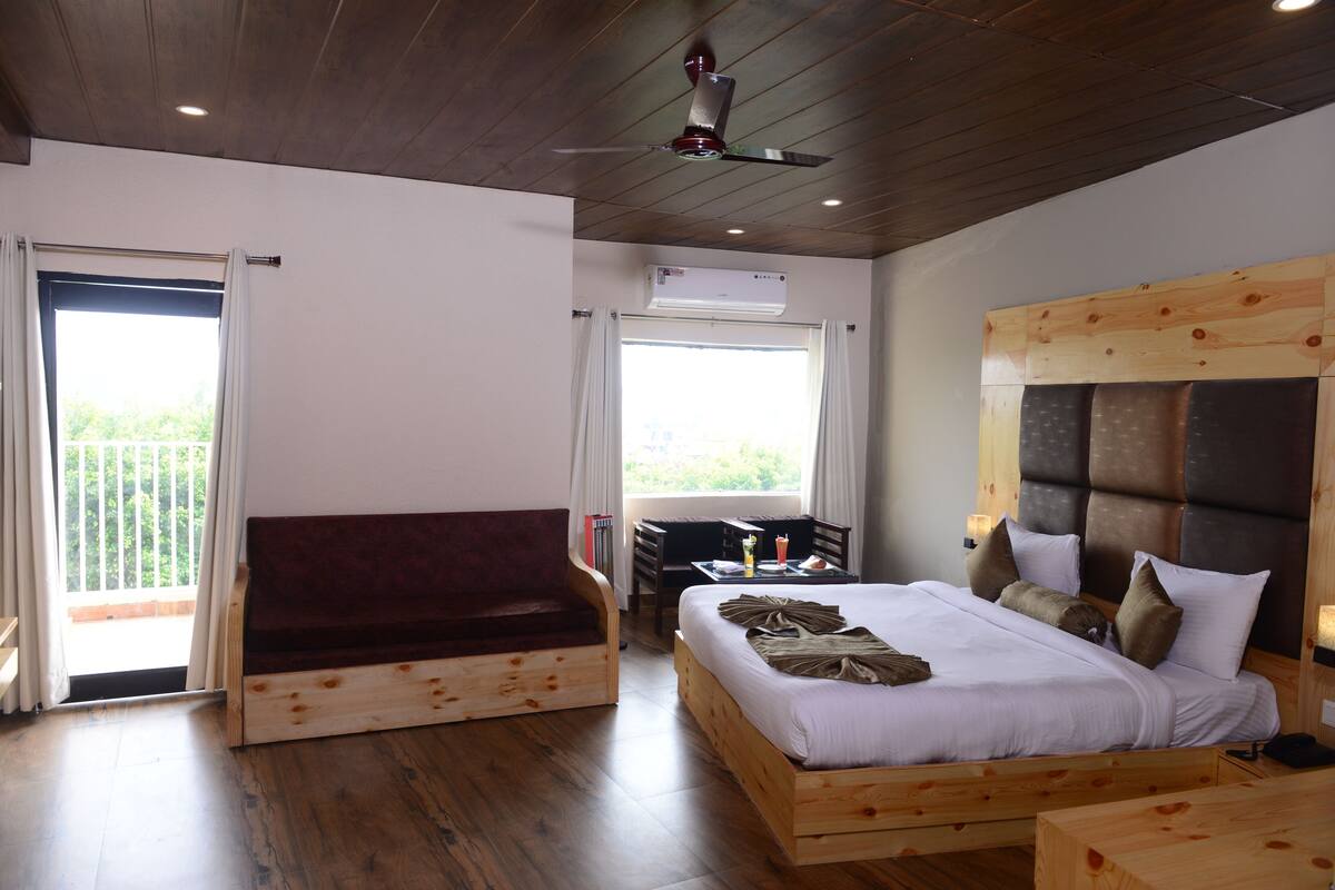 A bedroom with a wooden bed, a wooden bench, a ceiling fan, and an air conditioning unit.