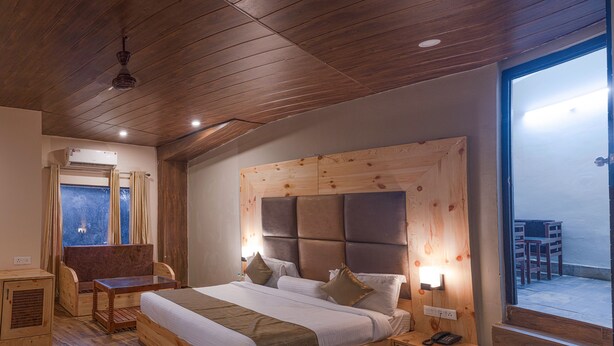 A wooden-framed bed with a headboard, bedside tables, and a window with curtains. - The Tattwaa Corbett Spa & Resort (Ramnagar)