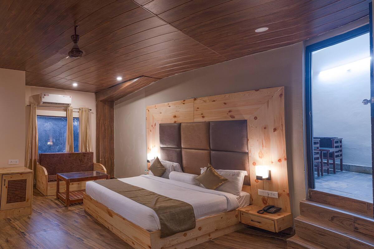 A wooden-framed bed with a headboard, bedside tables, and a window with curtains.