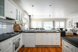 Une cuisine moderne avec des meubles blancs, un plan de travail noir, un lave-vaisselle encastré et une cuisinière à gaz.