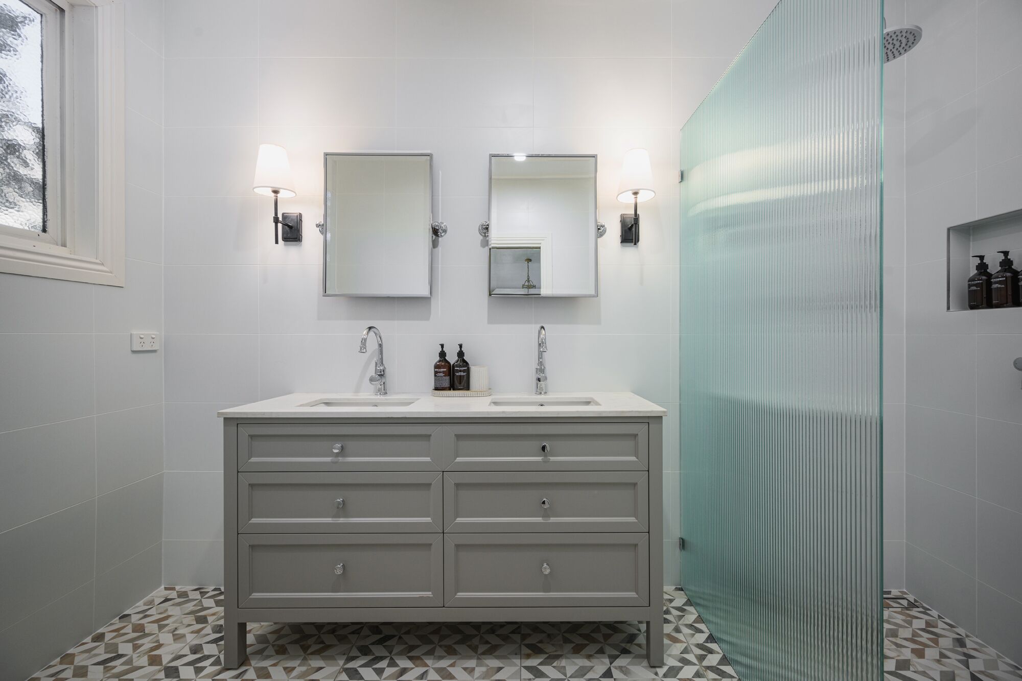 A modern bathroom with two sinks, a large mirror, and a glass shower enclosure.