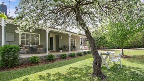 A house with a covered porch, outdoor seating, and a well-maintained lawn. - Beautiful spacious home a short walk to town centre. (Bright)