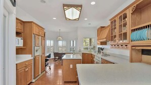 A spacious kitchen with wooden cabinets, a central island, and a large window providing natural light. - Mountain Views | Pool Table | Spacious 4BR (Prescott)
