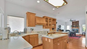 A spacious kitchen with wooden cabinets, a central island, and a dining area with a table and chairs. - Mountain Views | Pool Table | Spacious 4BR (Prescott)