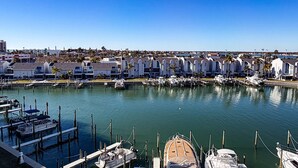 A marina with docked boats and a row of white buildings with sloped roofs.