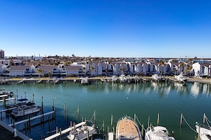 Un port de plaisance avec des bateaux amarrés et une rangée de bâtiments blancs aux toits inclinés.