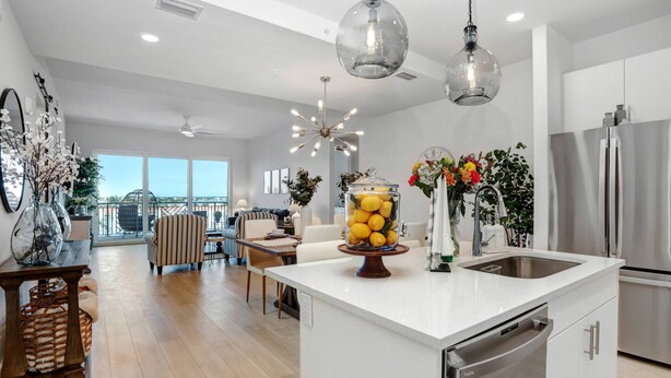 A modern kitchen with a central island, stainless steel appliances, and a dining area with a view.