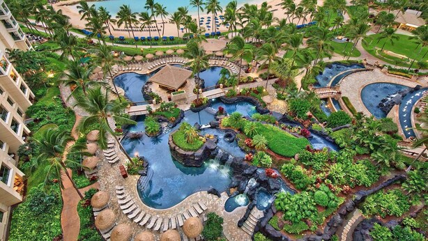 A resort with multiple swimming pools, palm trees, and a beach.