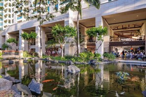 Guests can enjoy serene views of the outdoor pond with koi fish and lush greenery from the hotel's modern rooms with large windows and balconies.