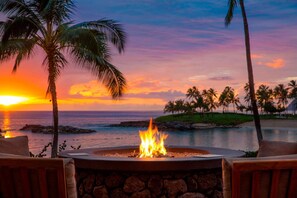 Relax in a serene outdoor seating area with a fire pit, surrounded by a wall and overlooking the ocean.
