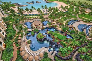 Un resort con varias piscinas, palmeras y una playa.