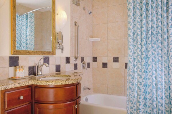 Un baño con lavabo, tocador, espejo, ducha y bañera.