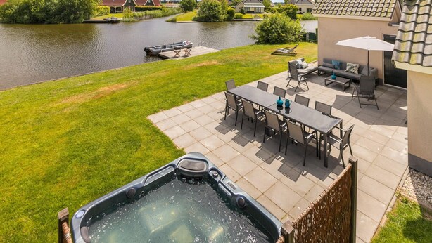 Un espace patio avec un jacuzzi, du mobilier d’extérieur et une vue sur une rivière.