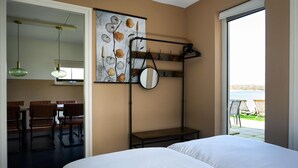 Une chambre d’hôtel comprenant un lit, un coin repas avec des chaises et une table, un grand miroir et une vue sur l’extérieur.