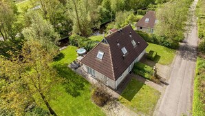 A residential property with a paved driveway, a small garden, and a river in the background. - Bungalow in Friesland with Outdoor Spa (Friesland)
