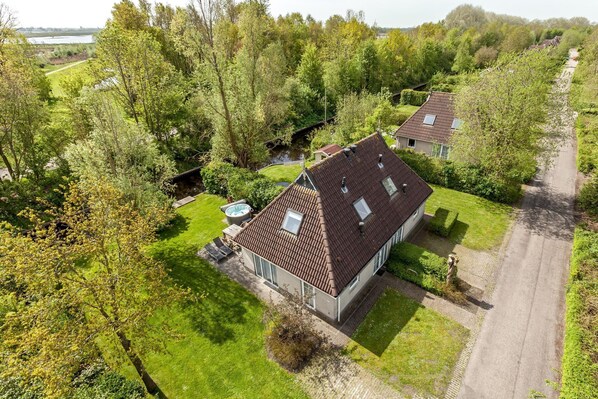 A residential property with a paved driveway, a small garden, and a river in the background.