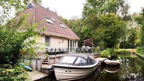 Ein Haus mit rotem Ziegeldach, einem Steg und einem Boot namens "SUPER GRAND FLYER 4", das an der Pier anliegt.