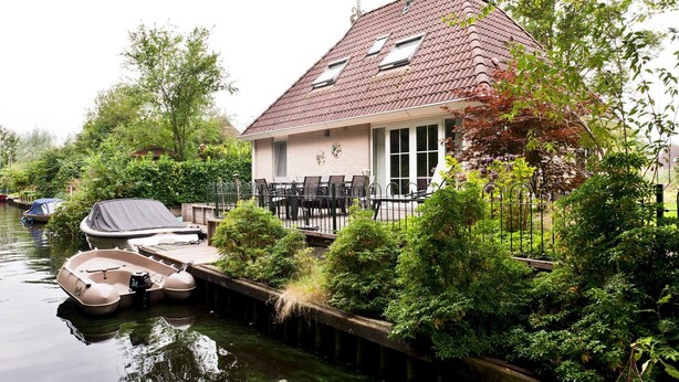 Ein Haus mit einem Steg, einem Boot und einem Garten.