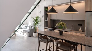 A modern kitchen with a central island, pendant lighting, and a view of the living area. - Urban Oasis - Walking distance to the Old Town, the beach and all kind of shops! (Chania)