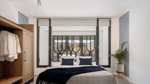 A modern bedroom with a large bed, a wardrobe, and a view through a sliding door. - Urban Oasis - Walking distance to the Old Town, the beach and all kind of shops! (Chania)