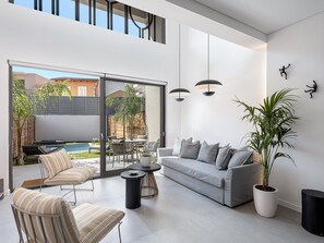 Ein modernes Wohnzimmer mit einem grauen Sofa, gestreiften Sesseln, einem Couchtisch und einer Topfpflanze.