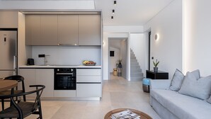 A modern kitchen with integrated appliances, a dining area with a table and chairs, and a living room with a sofa and a coffee table. - Urban Oasis - Walking distance to the Old Town, the beach and all kind of shops! (Chania)