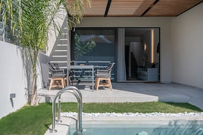Une terrasse extérieure moderne dotée d'une piscine, d'un coin repas avec des meubles en osier et d'un escalier menant à un espace intérieur.