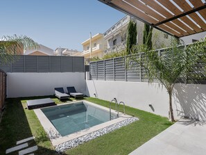 Un espace piscine extérieur moderne comprenant une piscine rectangulaire, des chaises longues et une pergola.