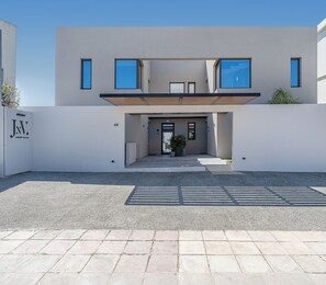 Un bâtiment moderne doté d’un toit plat, de grandes fenêtres et d’un espace d’entrée pavé.