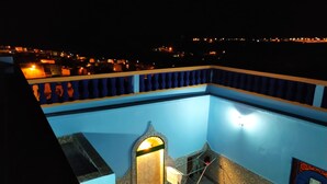 A rooftop pool with a blue and yellow railing, surrounded by a cityscape at night. - Casa Morisca Classic (Sidi Ifni)