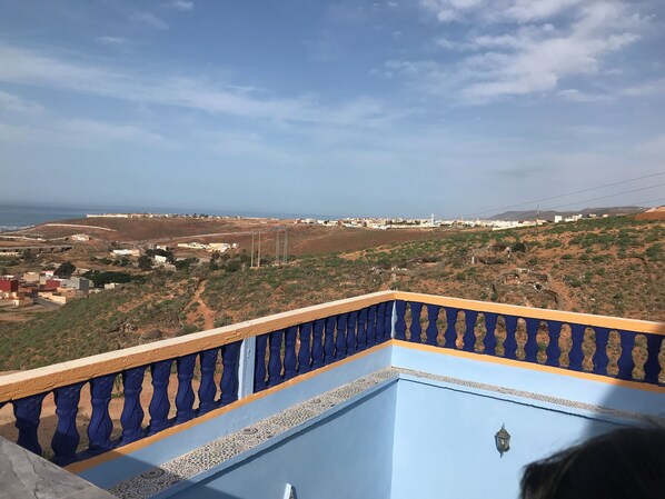 Un balcón con vistas a un paisaje costero, que incluye edificios y un faro.